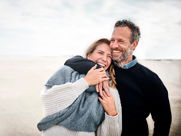 Una pareja sonriendo felices con una sonrisa perfecta gracias al seguro dental de AXA