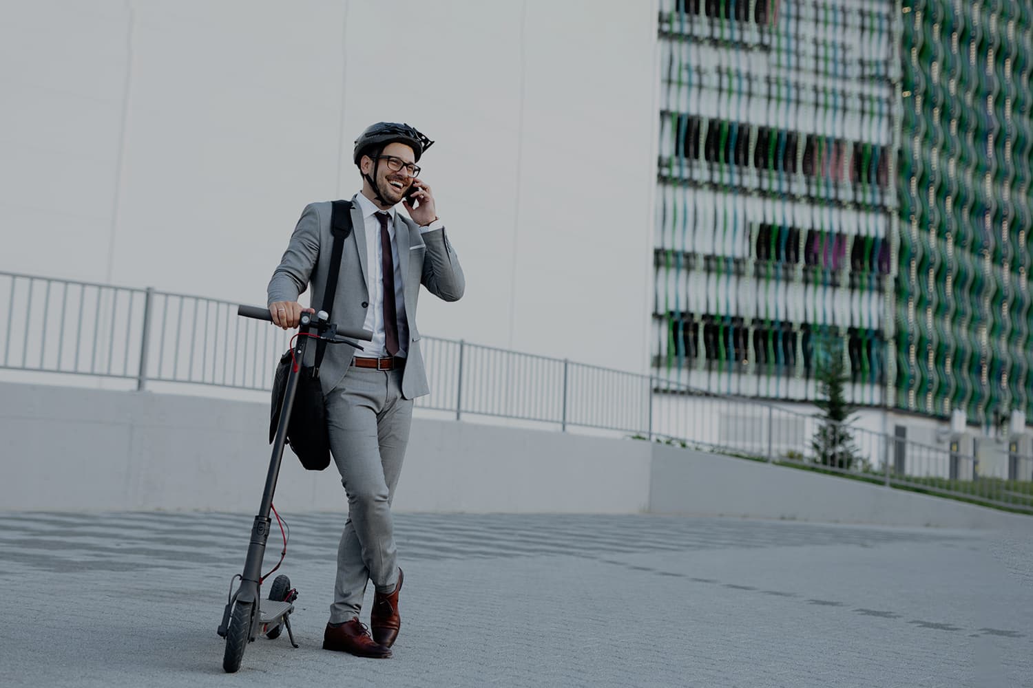 fotografía de un hombre hablando por teléfono mientras sostiene un patinete eléctrico